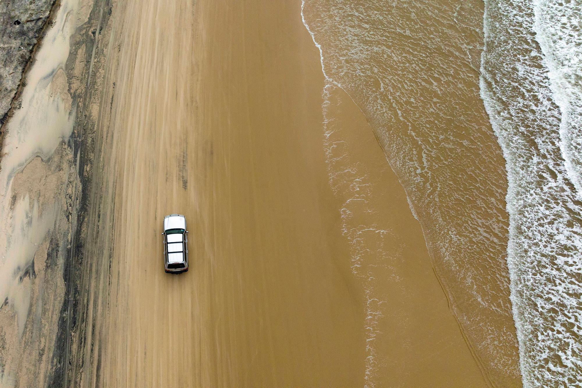 Luftaufnahme von einem SUV an einem Strand.