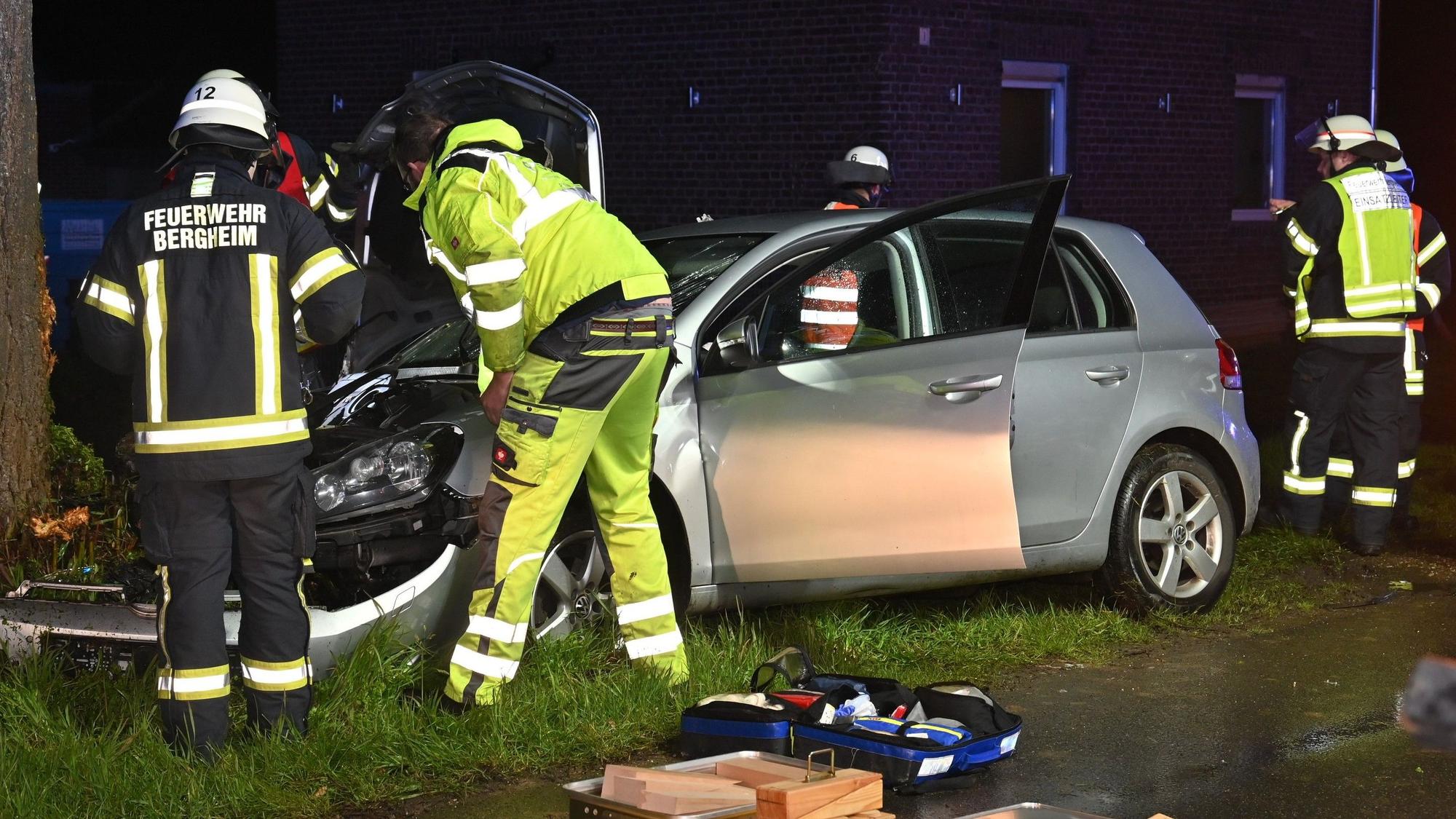 Das Bild zeigt Einsatzkräfte der Feuerwehr Bergheim an dem silbernen VW-Golf. Das Fahrzeug war gegen einen Baum geprallt.