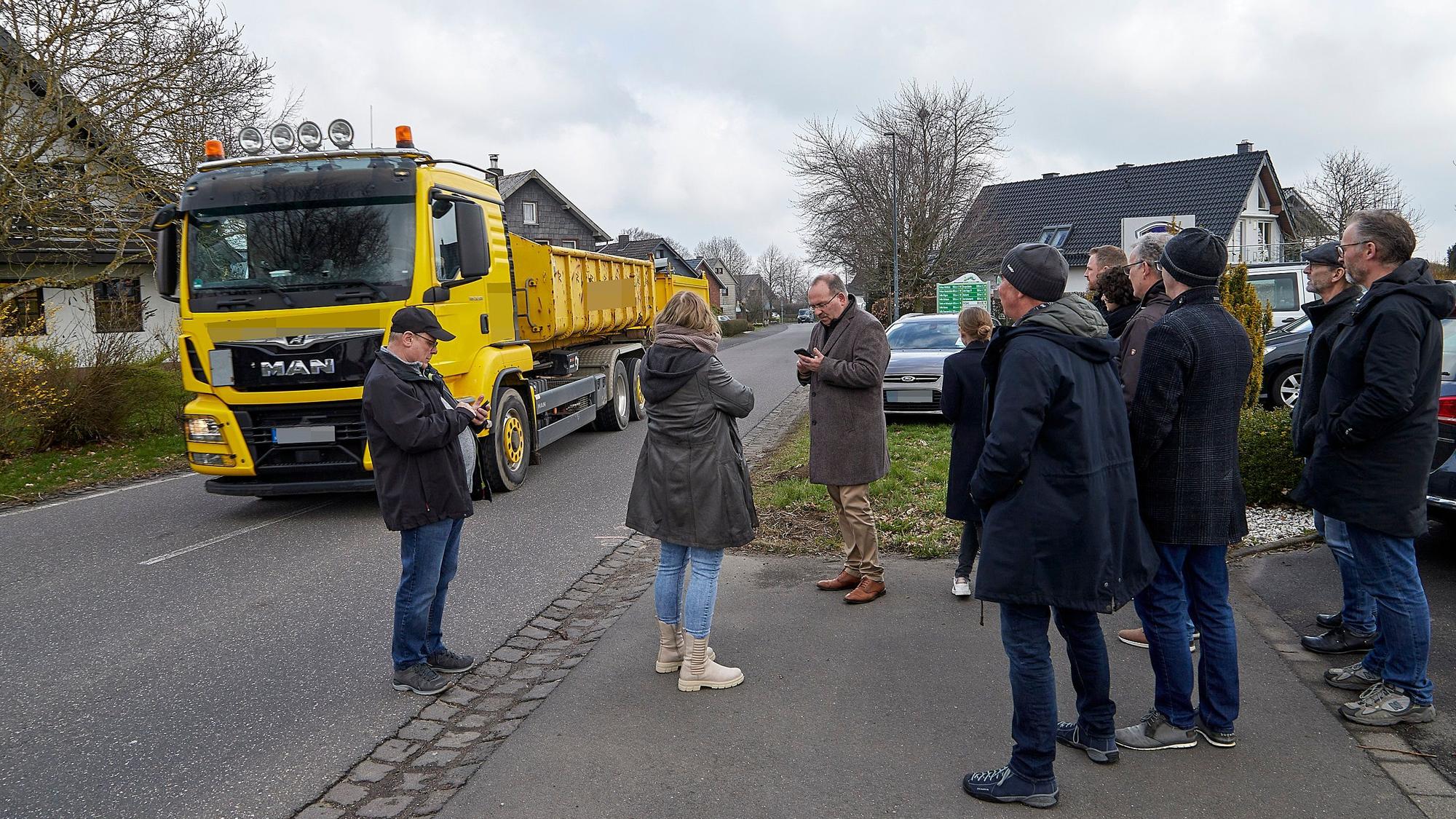 Während die Besucher am Straßenrand stehen, rollt ein Lastwagen mit Anhänger auf dem Mittelstreifen durch den Ort
