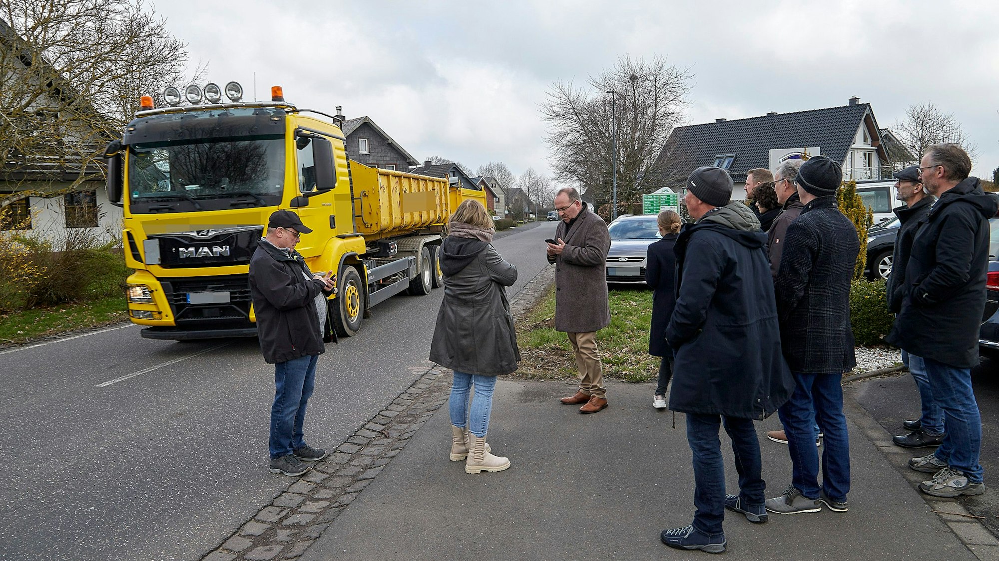 Während die Besucher am Straßenrand stehen, rollt ein Lastwagen mit Anhänger auf dem Mittelstreifen durch den Ort