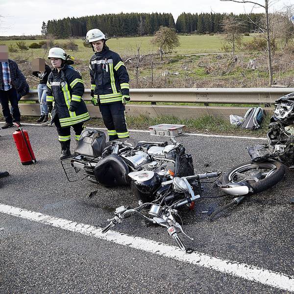 Feuerwehrleute sichern die Unfallstelle. Das Motorrad ist völlig zerstört, der Pkw im Bereich des Motors.