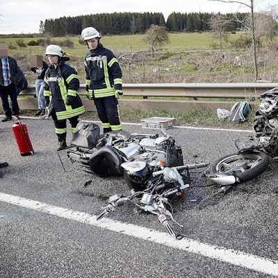 Feuerwehrleute sichern die Unfallstelle. Das Motorrad ist völlig zerstört, der Pkw im Bereich des Motors.