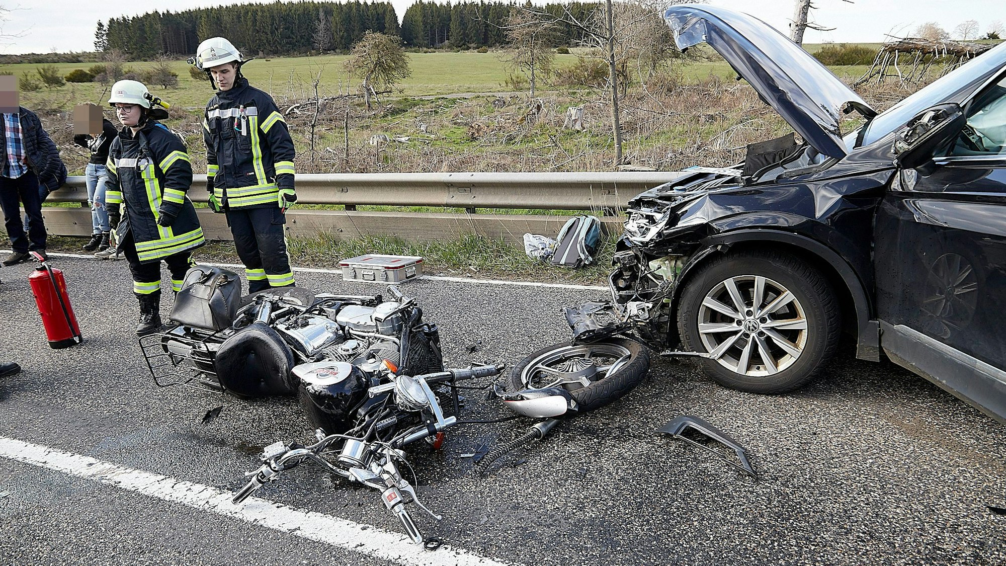 Feuerwehrleute sichern die Unfallstelle. Das Motorrad ist völlig zerstört, der Pkw im Bereich des Motors.