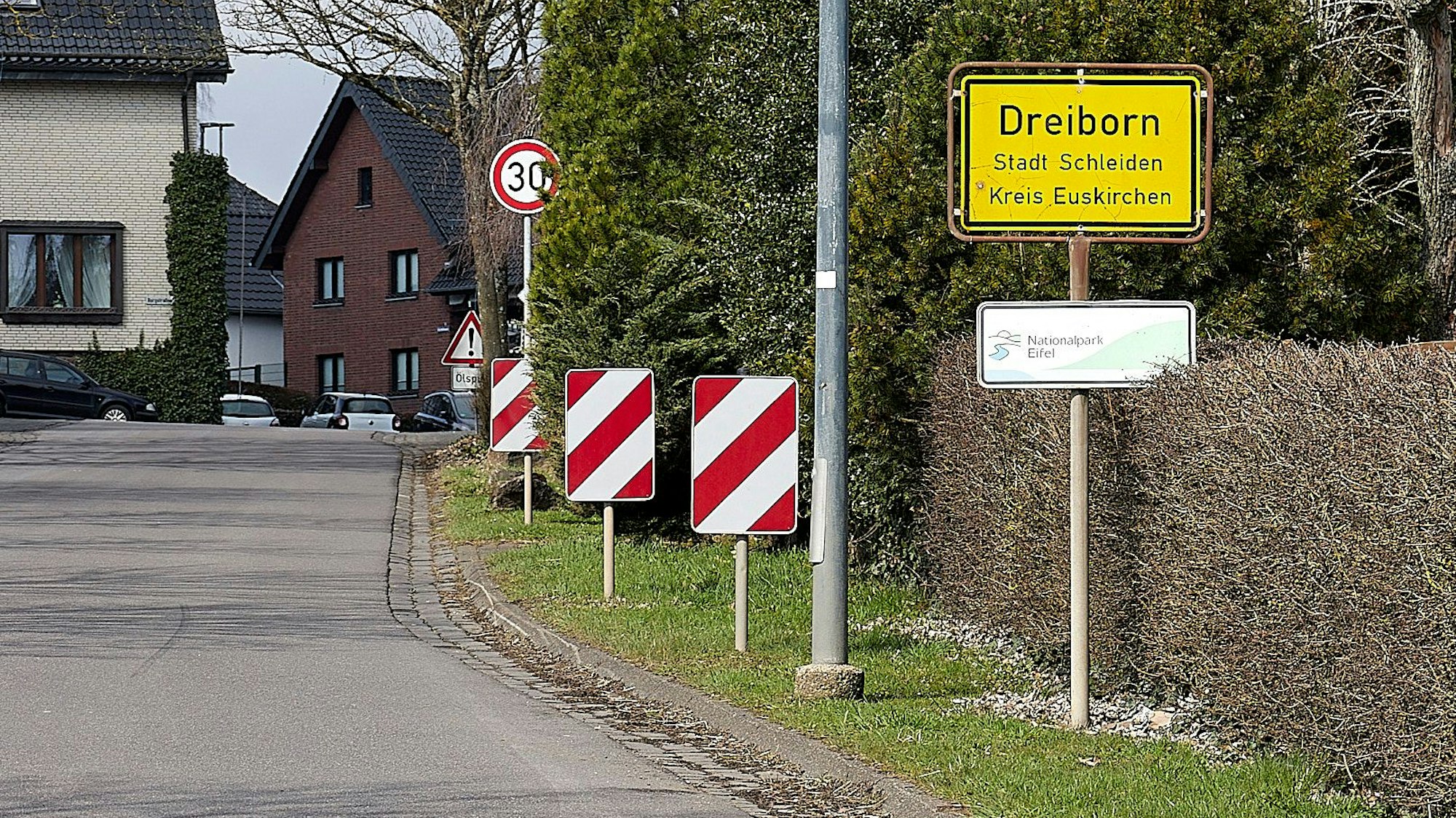 Am Ortseingangsschild verengt sich die Straße. Ein Schild gebietet maximal Tempo 30 km/h.