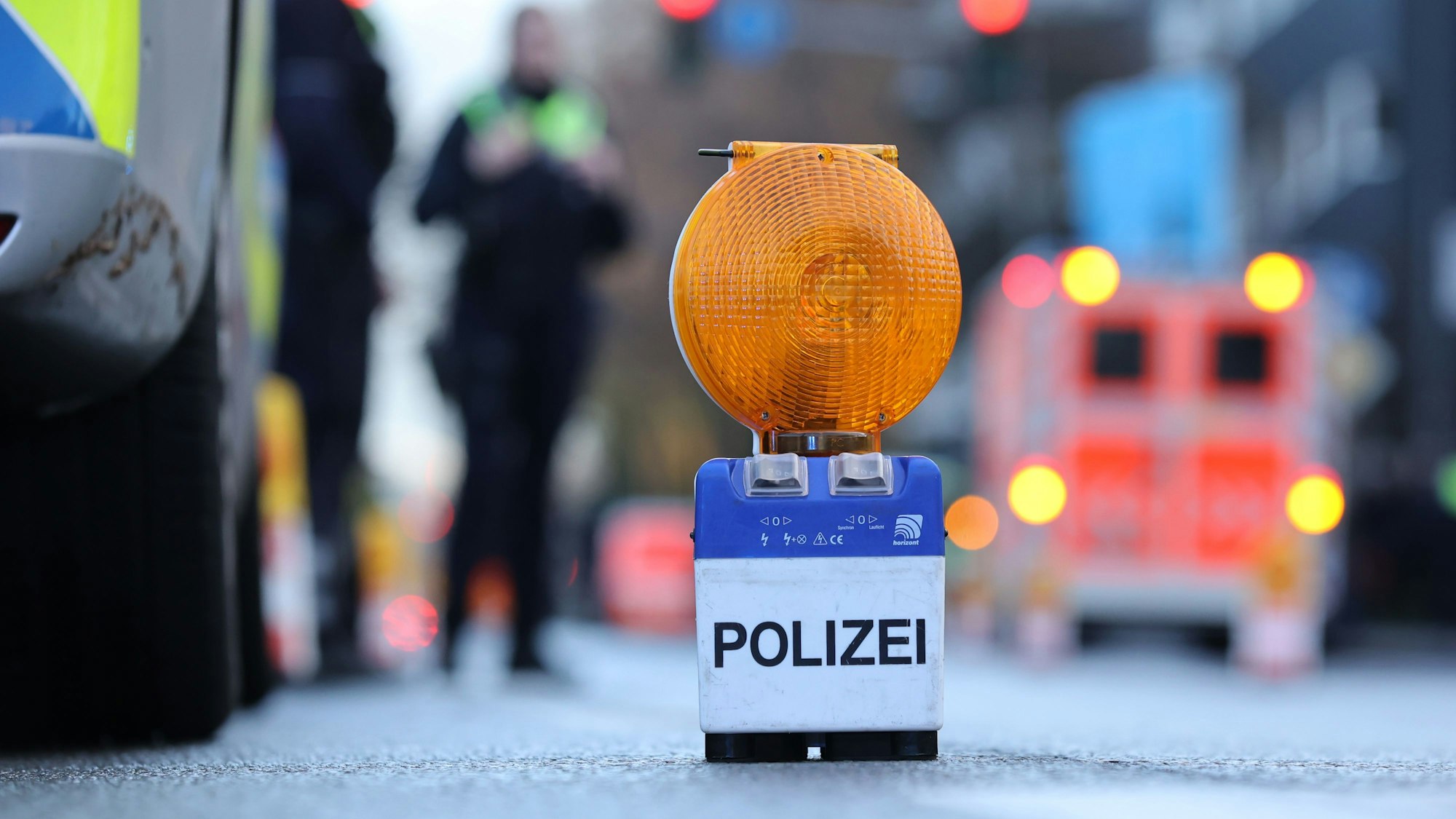 Eine Polizei-Warnbake steht auf einer Straße in Köln (Symbolbild). Nach einem schweren Unfall in Köln ist ein 64-jähriger Mann verstorben.