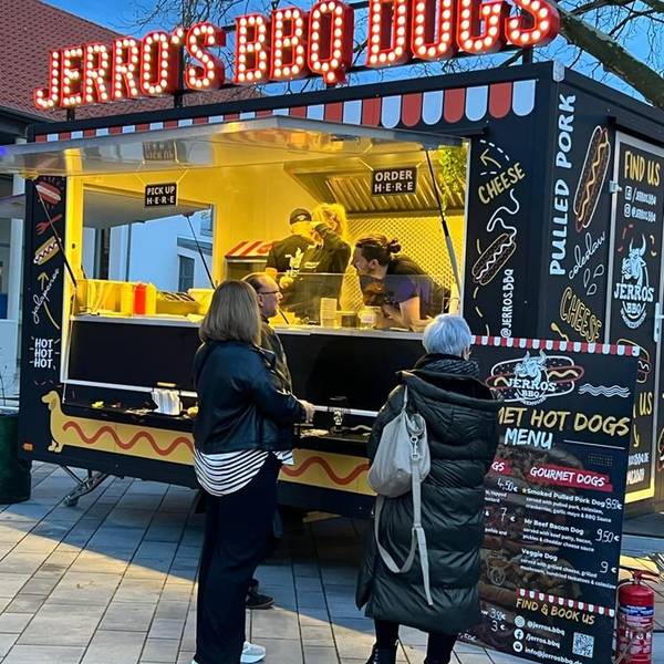 Es ist ein Streetfood-Wagen zu sehen, vor dem mehrere Leute stehen.