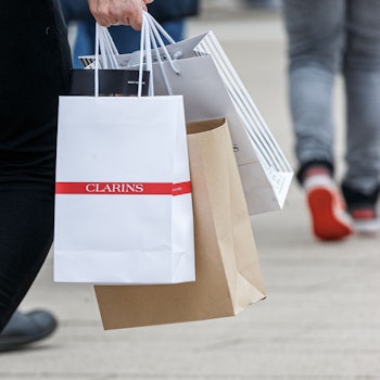 Ein Mann geht mit Einkaufstüten durch eine Innenstadt.