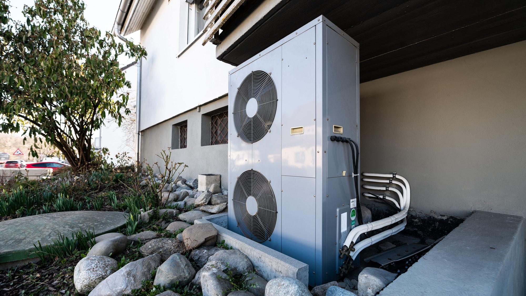 Die Lüftungsanlage einer Wärmepumpe steht vor einem Wohnhaus