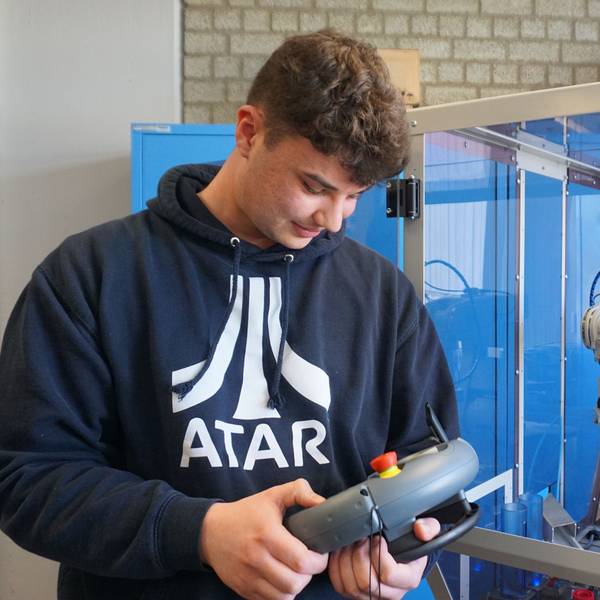 Berufsschüler Liam Allen führt die neue Robotik-Anlage am Thomas Esser Berufskolleg vor.