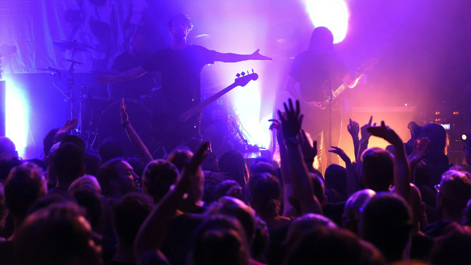 Eine Menschenmenge vor einer Bühne, darauf Gitarristen.