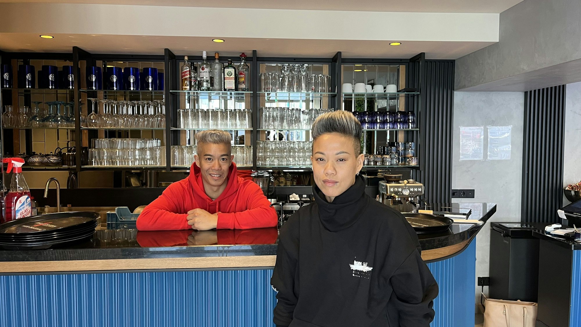 Bruder und Schwester stehen an der Bar ihres Restaurants.
