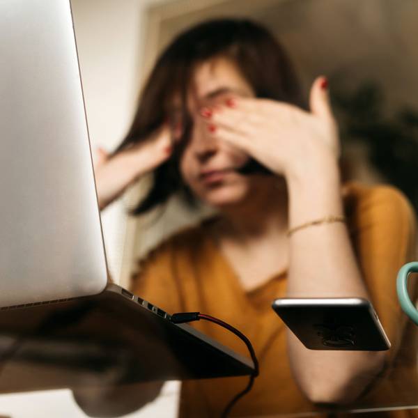 Junge Frau reibt sich die Augen vor ihrem Laptop