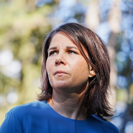 Bundesaußenministerin Annalena Baerbock (Grüne) blickt links neben die Kamera. Hinter der Politikerin ist unscharf ein Baum zu erkennen.