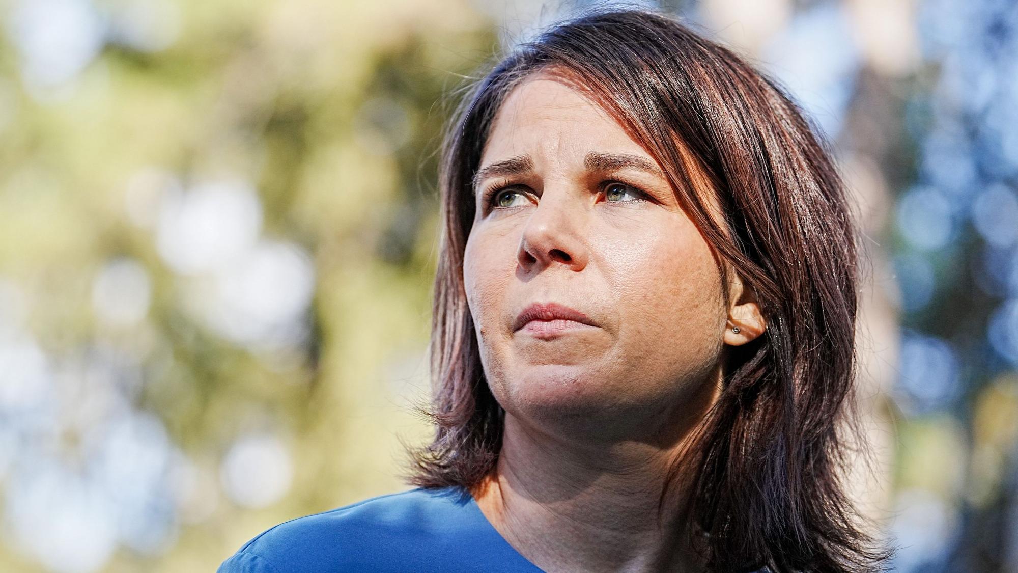 Bundesaußenministerin Annalena Baerbock (Grüne) blickt links neben die Kamera. Hinter der Politikerin ist unscharf ein Baum zu erkennen.