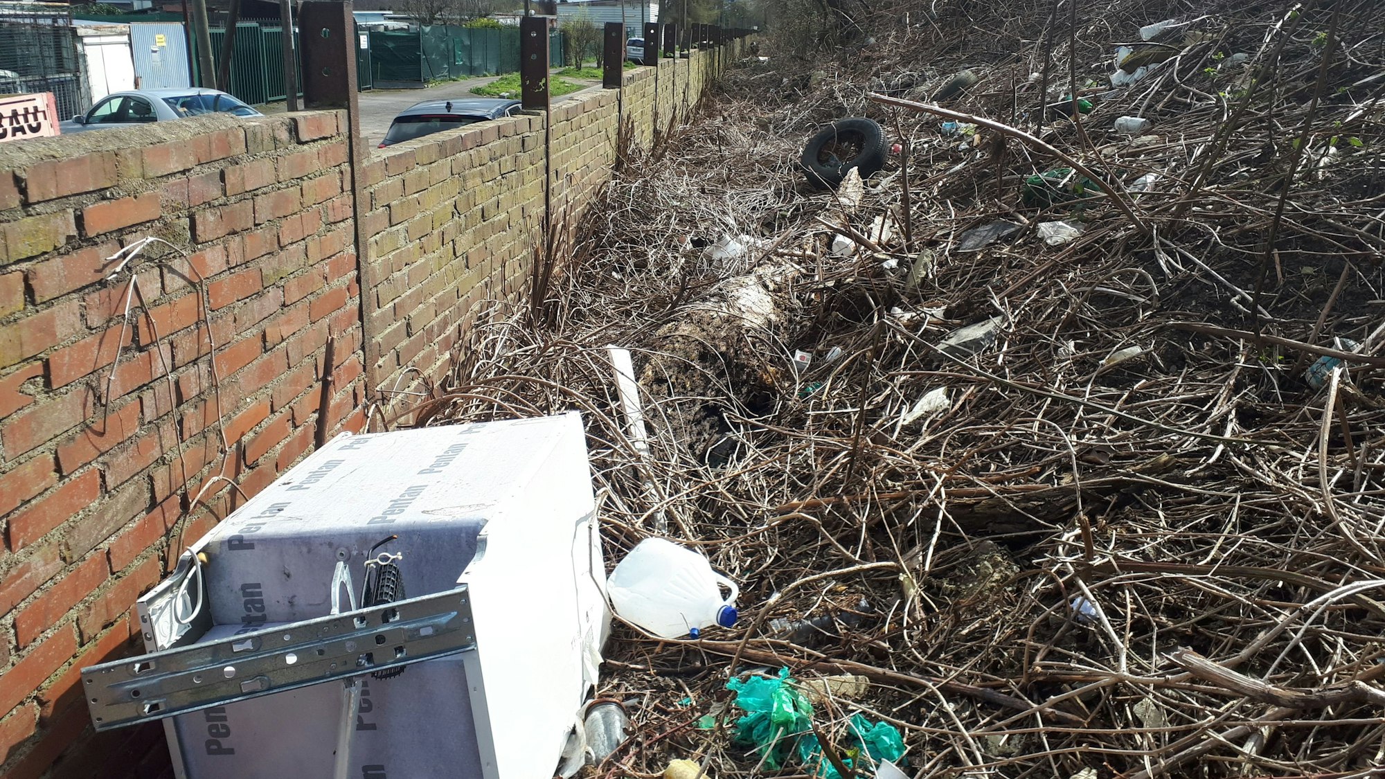 Eine alte Waschmaschine, Plastikkanister, Autoreifen und sonstiger Unrat türmt sich hinter einer Bahndamm-Mauer an der Etzelstraße.
