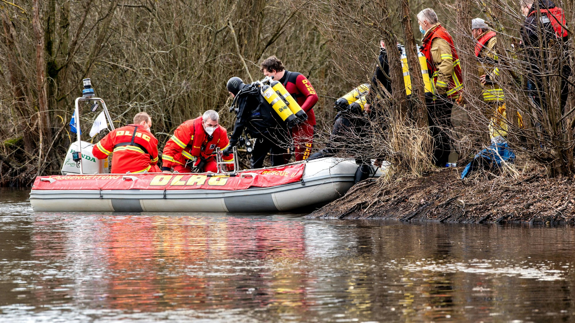 Einsatzkräfte von DLRG und Feuerwehr sind mit einem Boot an einem Teich im Einsatz.