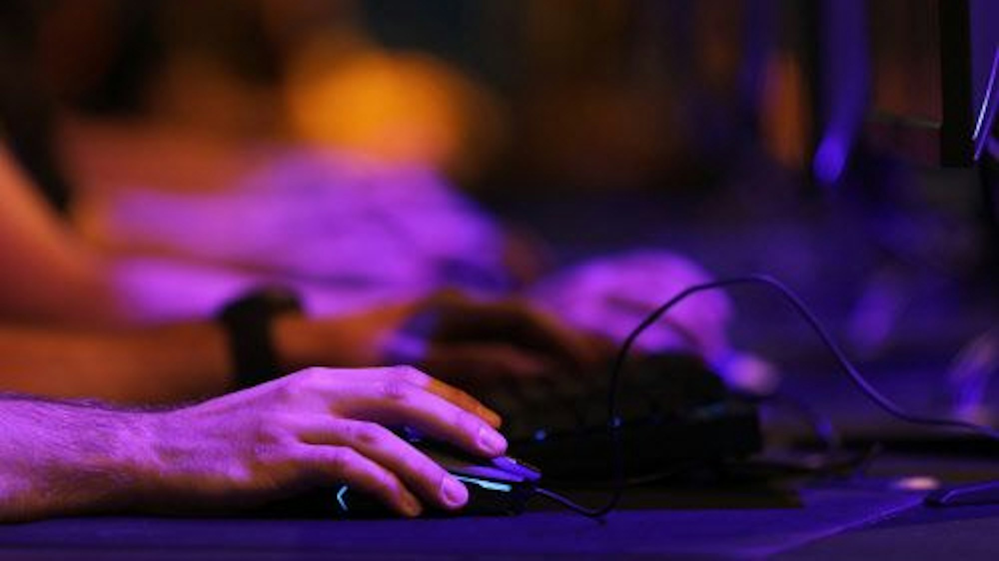 Eine Männerhand benutzt vor dem Computer sitzend die Maus.