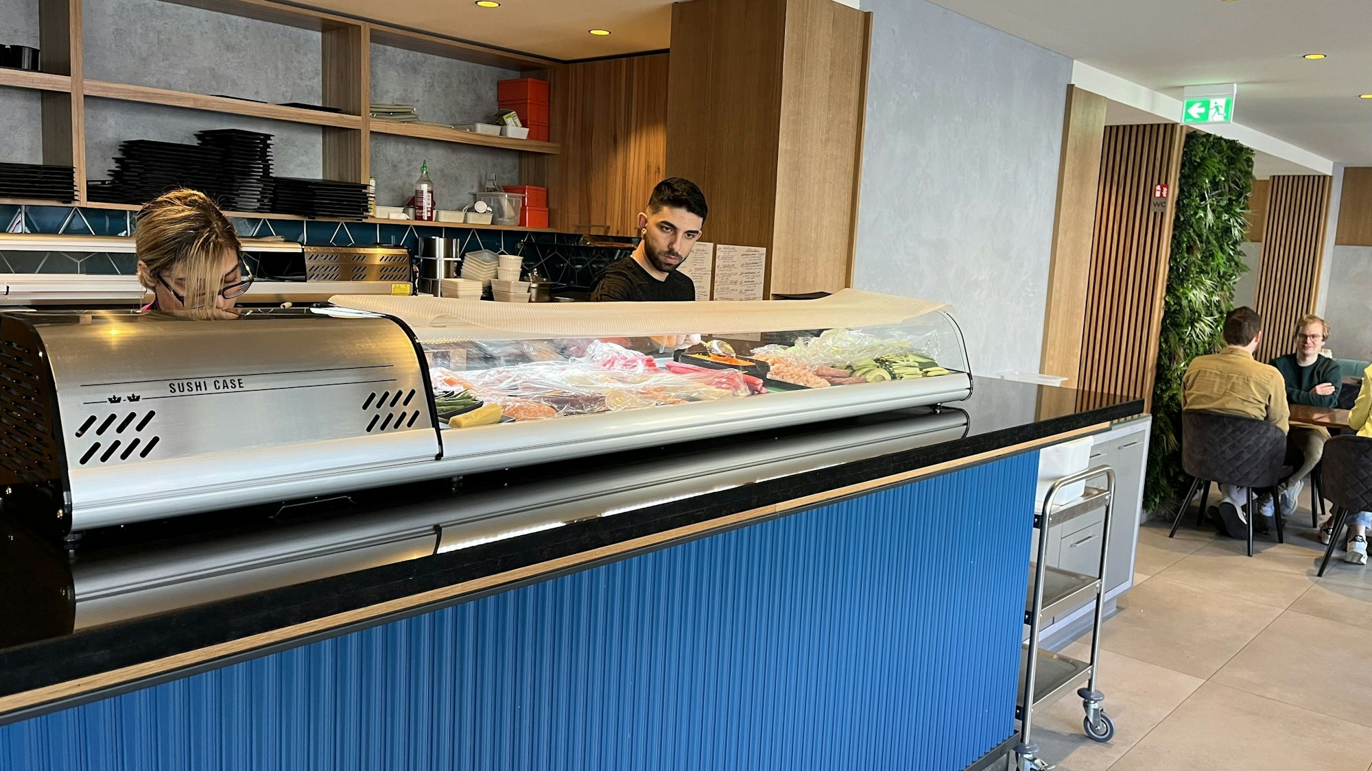 Zwei Köche stehen hinter der Sushibar.