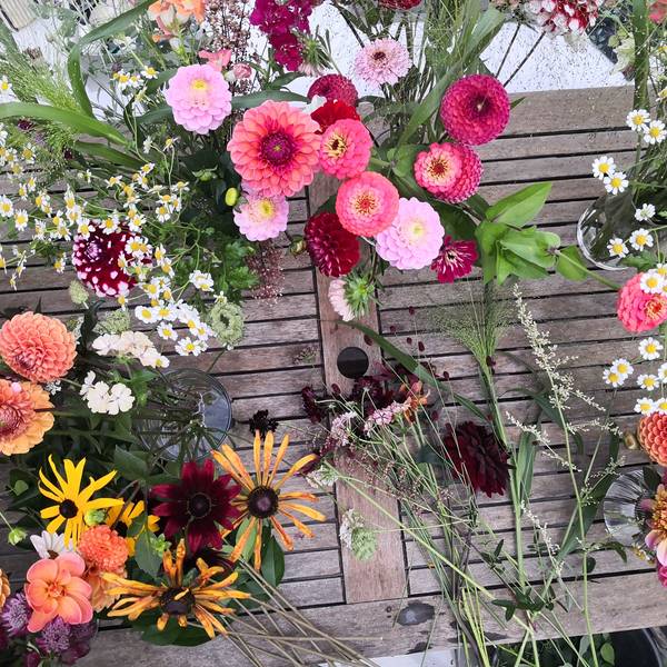 Blumen liegen bei Rheinblüten auf einem Tisch und stehen in Vasen.