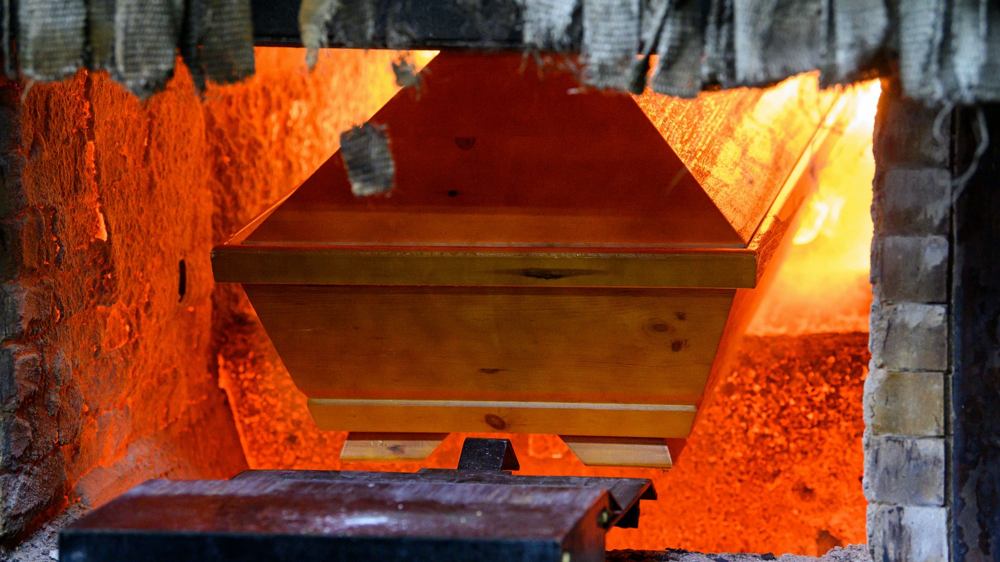 Ein Sarg wird in einem Krematorium in den Einäscherungsofen eingefahren.