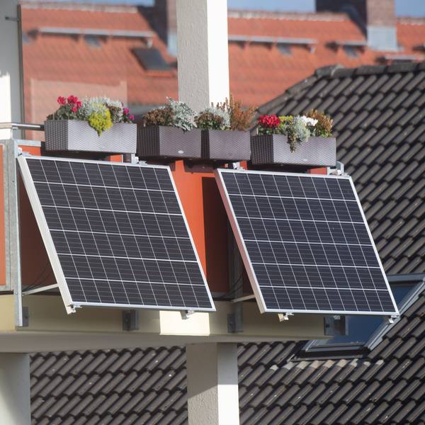 Solarmodule für ein sogenanntes Balkonkraftwerk hängen an einem Balkon.