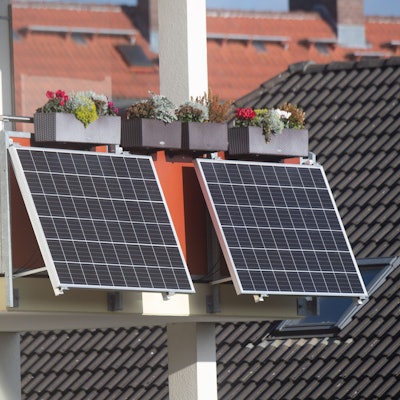 Solarmodule für ein sogenanntes Balkonkraftwerk hängen an einem Balkon.