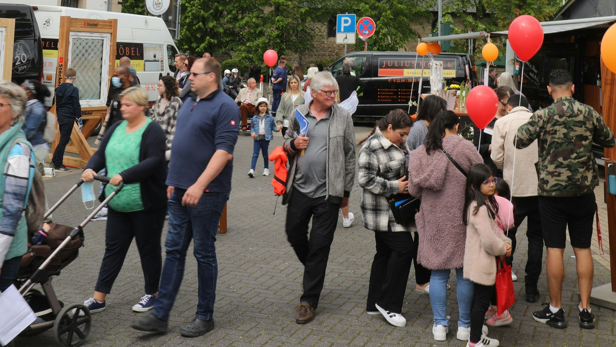 Menschen halten Luftballons und schlendern über das Fest.