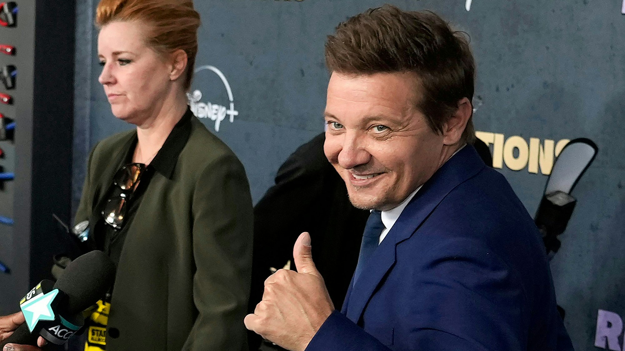 Jeremy Renner hält seinen Daumen hoch und guckt in die Kamera.
