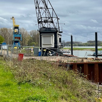 Hitdorfer Hafen, Kaimauer mit Krancafé im Vordergrund, hinten Hausboote im Hafen, dahinter der Rhein
