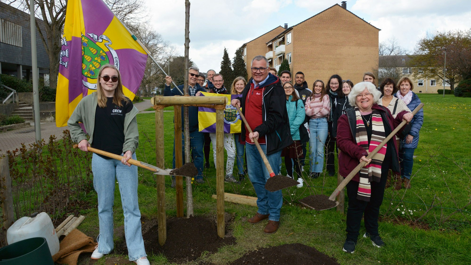 Baumpflanzung am Rathaus mit Flagge aus Funchal: (vorne von links) Mia-Anastasia von Schmudde (Crew-Verein), Bürgermeister Frank Steffes und Humberta Correia aus Funchal mit den Studentinnen und Studenten aus Madeira und Mitgliedern des Freundeskreises.