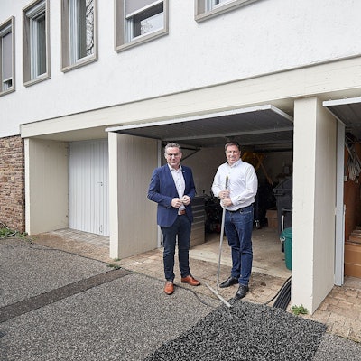 Bürgermeister Norbert Crump (l.) und Stefan Grieshaber stehen vor drei Garagen am Rathaus der Gemeinde Nettersheim in Zingsheim.
