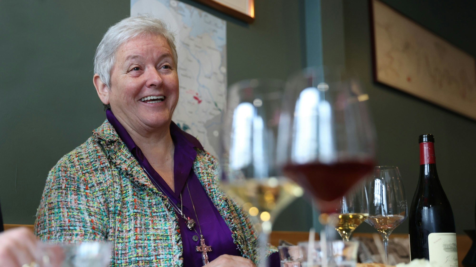 Frau mit kurzen grau-weißen Haaren sitzt an einem Tisch