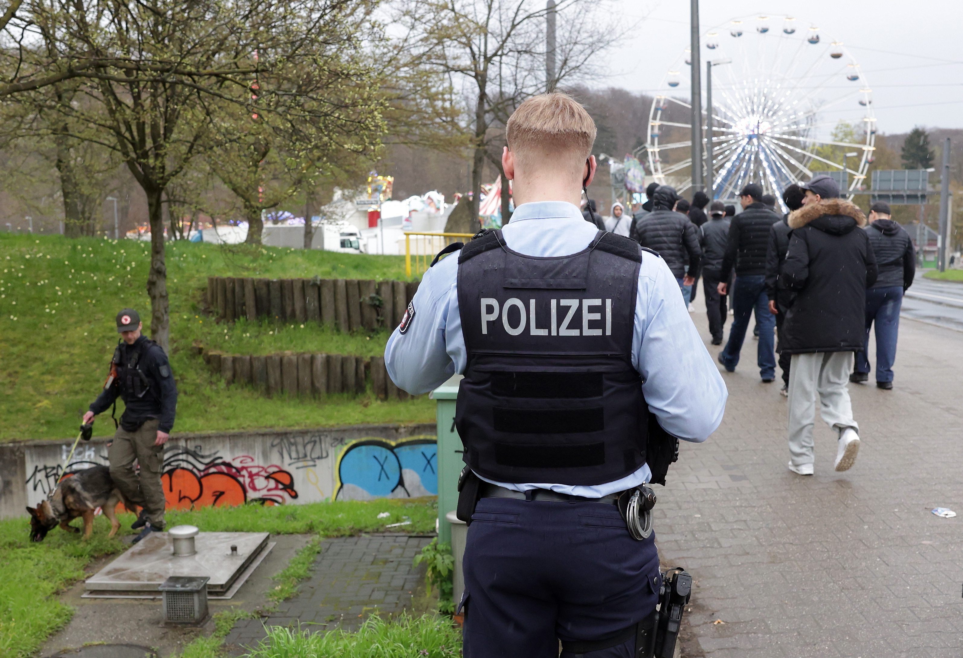 Ein Polizist sucht mit einem Hund nach der Tatwaffe. Bei einem Angriff mit einem Messer ist am 10.04.2023 ein 18-Jähriger schwer verletzt worden.