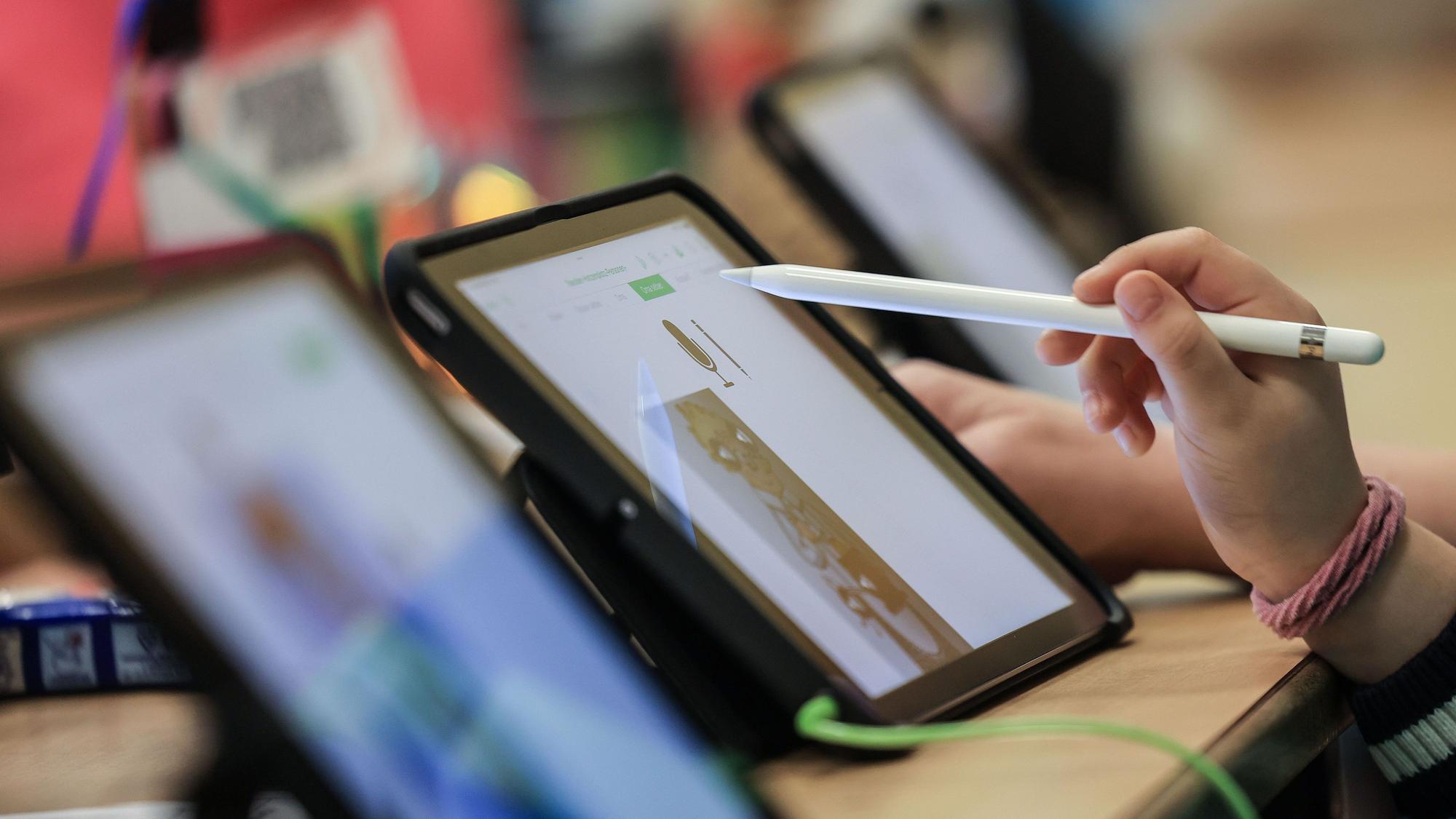 Die Hand eines Kindes hält einen Apple Pencil, der für die Bedienung eines iPads gebraucht wird. (Symbolbild)