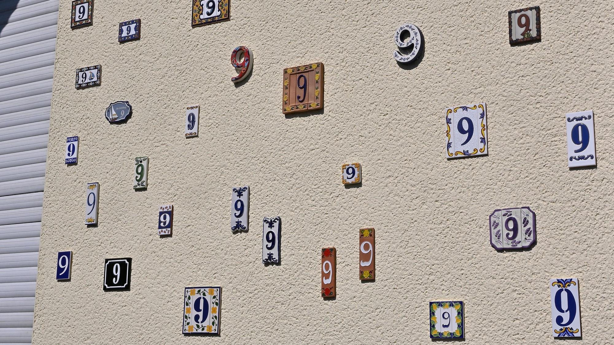 Das Foto zeigt eine Hauswand mit vielen Hausnummern.