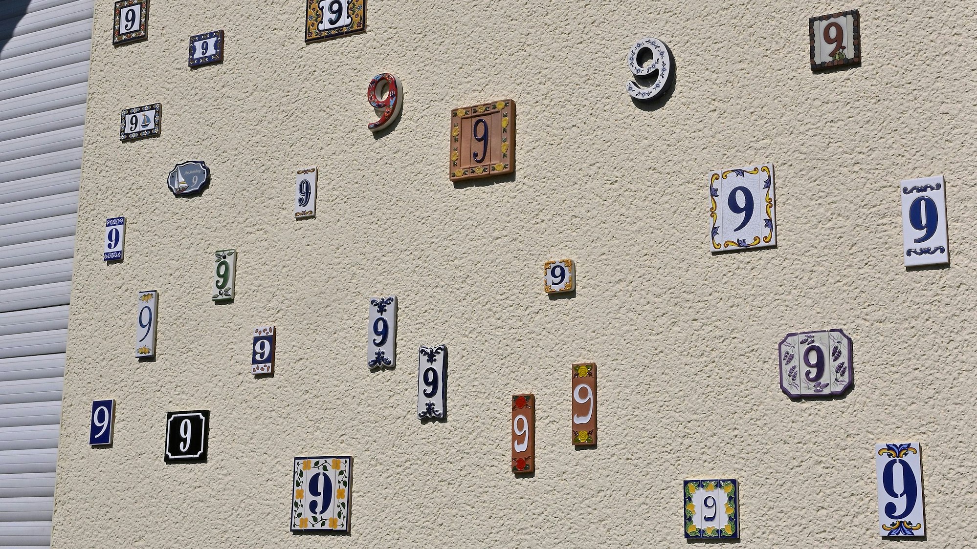 Das Foto zeigt eine Hauswand mit vielen Hausnummern.