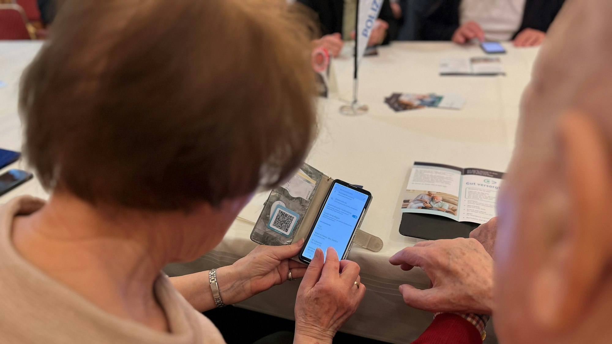 Eine Rentnerin und ein Rentner schauen gemeinsam auf ein Smartphone.