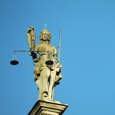 Justitia Statue aus Stein vor blauem Himmel. (Symbolbild)
