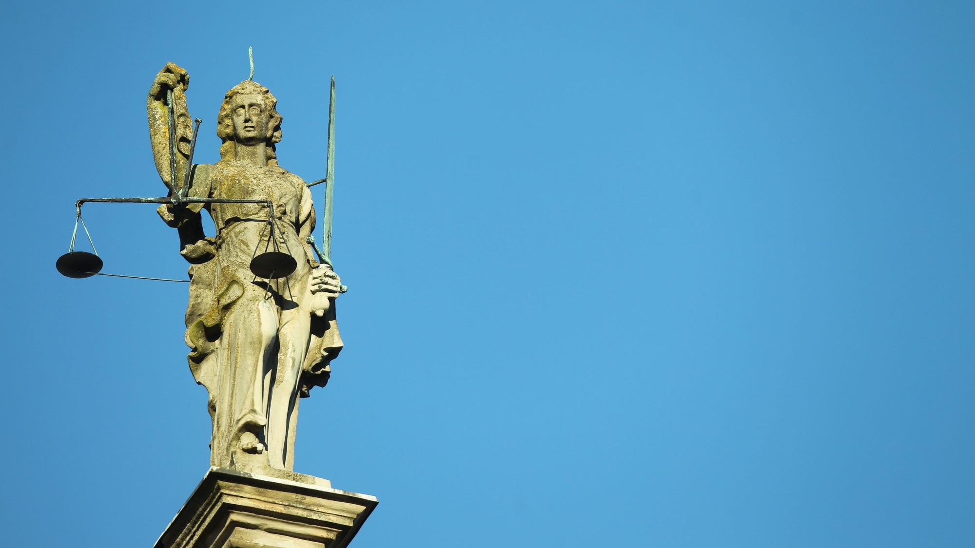 Justitia Statue aus Stein vor blauem Himmel. (Symbolbild)