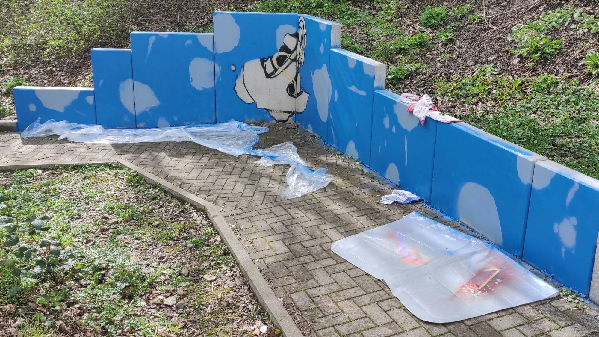 Abdeckplanen vor einer bemalten Stützmauer