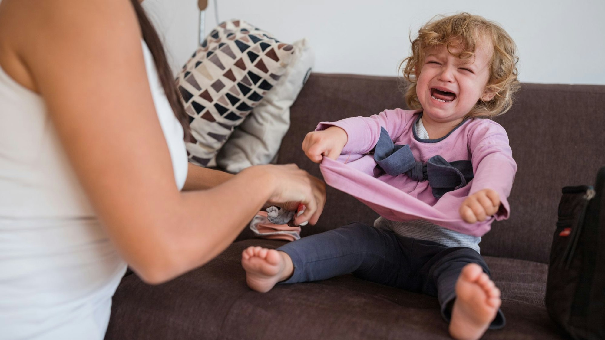 Ein Kleinkind schreit, weil es sich nicht anziehen möchte.