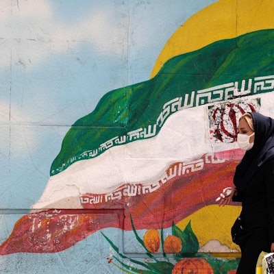 Frau läuft vor iranischer Flagge