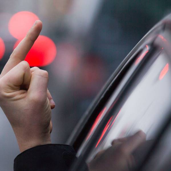 Ein Autofahrer streckt die Hand aus dem Fenster und zeigt den Mittelfinger.