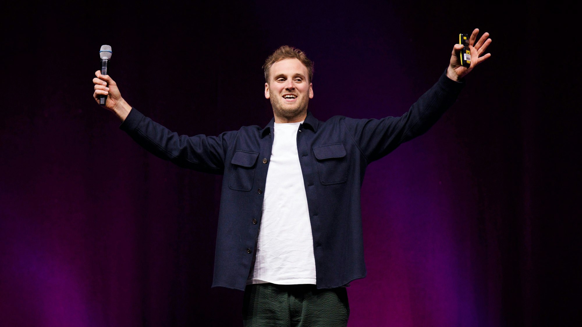 Psychologe und Autor Leon Windscheid steht mit ausgebreiteten Armen in der Lanxess-Arena. Er trägt ein weißes T-Shirt und ein blaues Hemd.