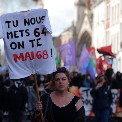 Eine Frau hält ein T-Shirt mit der Aufschrift „Ihr verhängt 64 Jahre, wir wiederholen Mai 68“ während einer Demonstration.