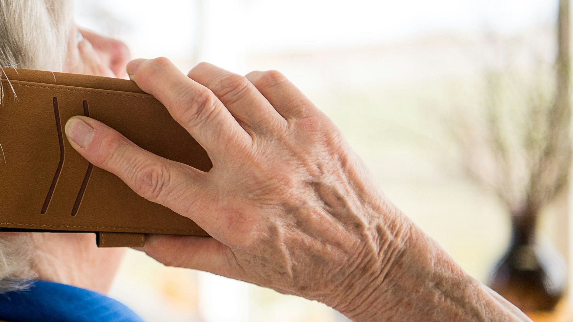 Eine ältere Person telefoniert mit Smartphone.