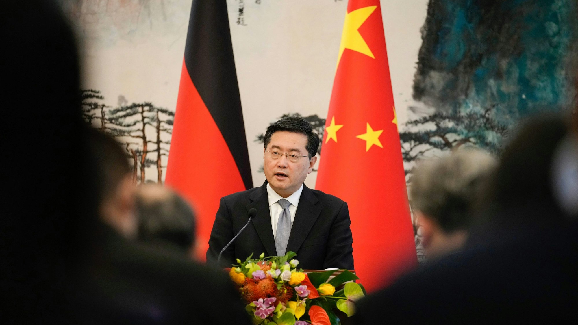Außenminister Qin Gang spricht vor einer chinesischen sowie einer deutschen Flagge.