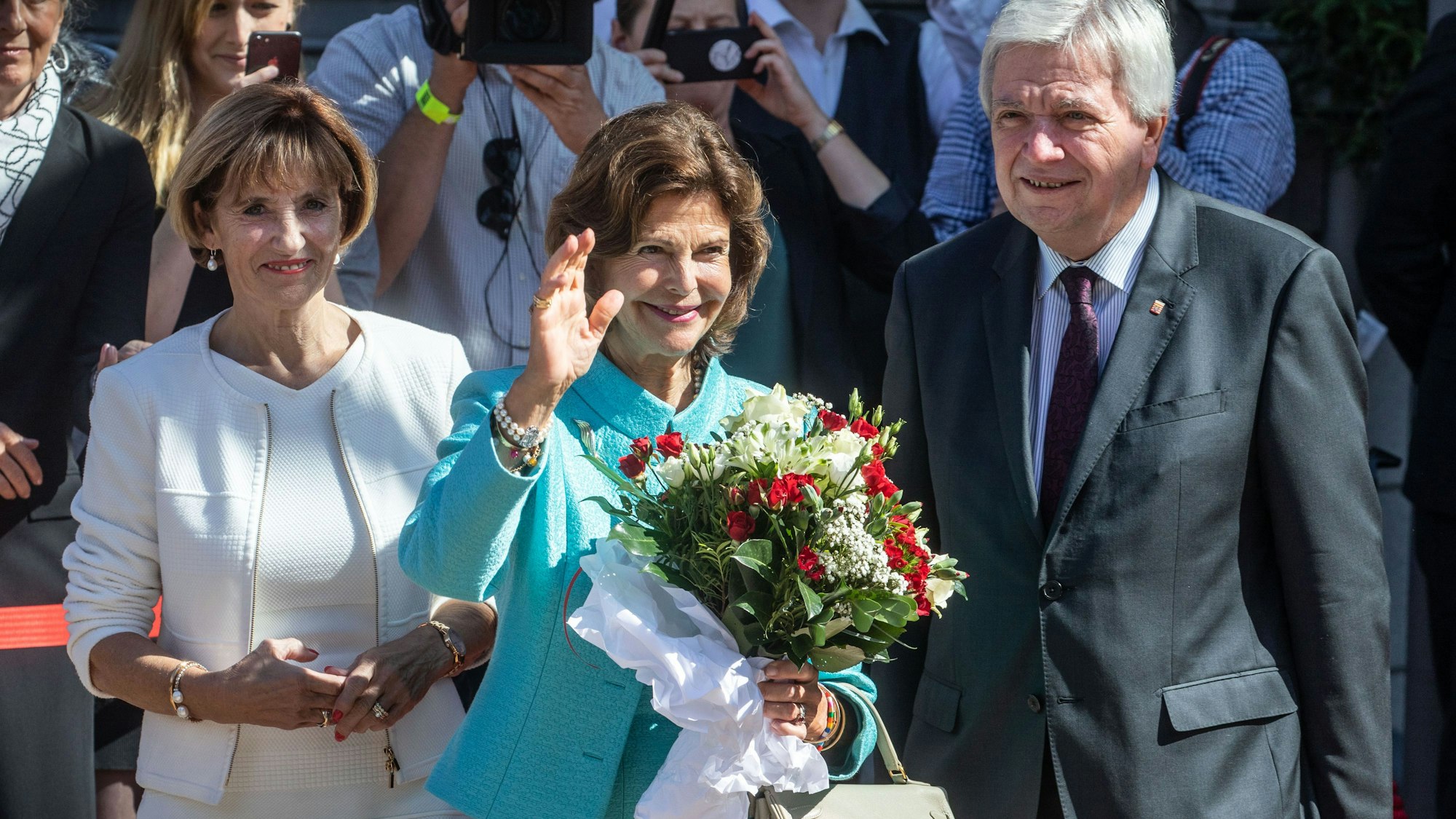 Königin Silvia von Schweden winkt den Zuschauern, während sie vor der Hessischen Staatskanzlei vom hessischen Ministerpräsidenten Volker Bouffier und dessen Frau Ursula empfangen wird.