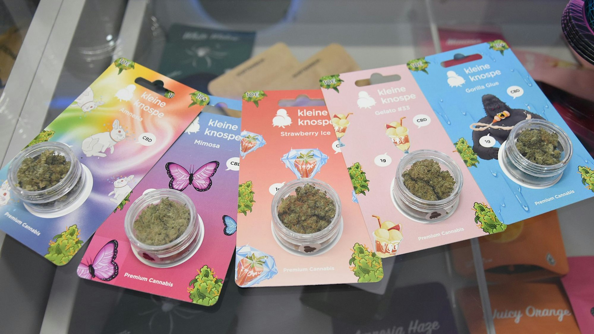 Mehrere Cannabis-Produkte liegen in bunten Verpackungen nebeneinander.