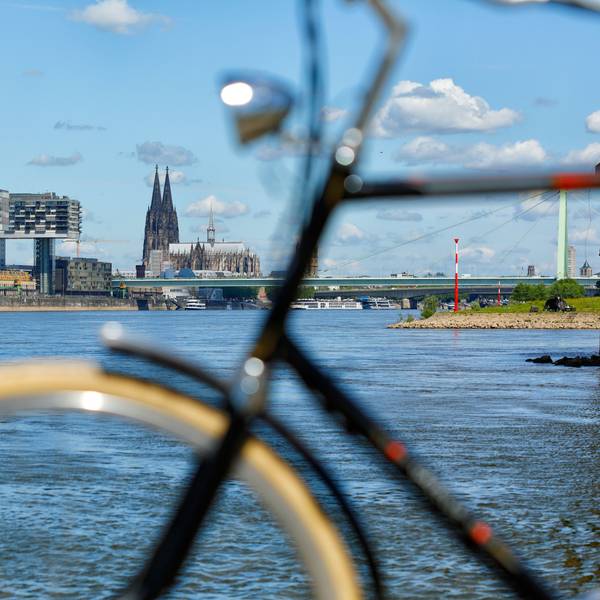 Fahrrad unscharf im Vordergrund vor Köln Kulisse mit Kranhäusern und Dom
